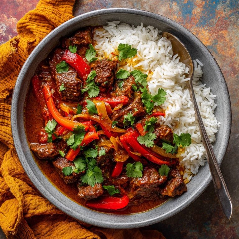 Herzhaftes Rindfleisch-Gulasch mit Paprika und Reis in einer Schüssel, serviert mit duftendem Reis und frischen Kräutern, von oben betrachtet.