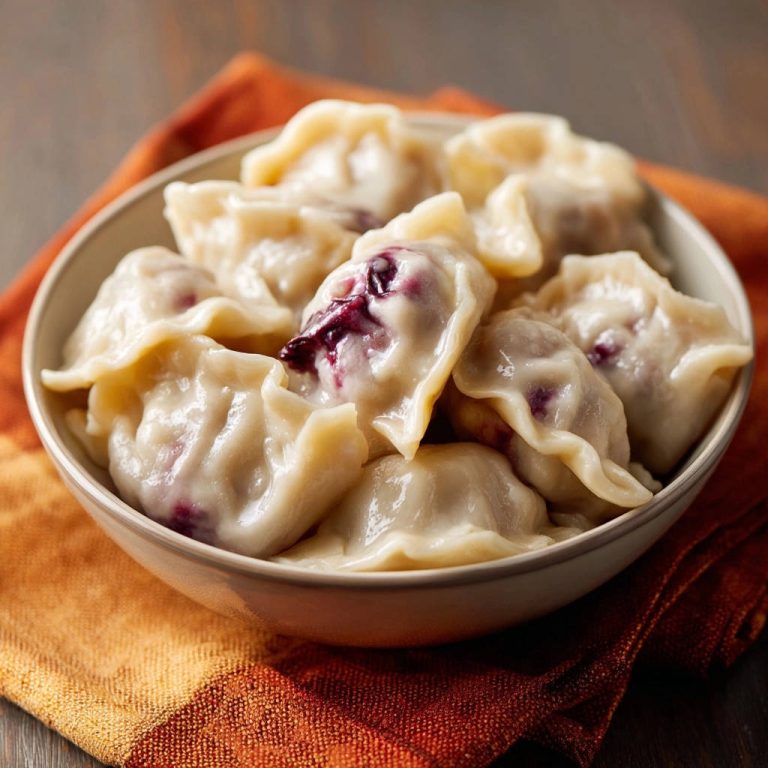 Saftige Blaubeer-Varenyky in einer Nahaufnahme, die die glänzende Oberfläche und die blaubeerige Füllung der Teigtaschen zeigt.