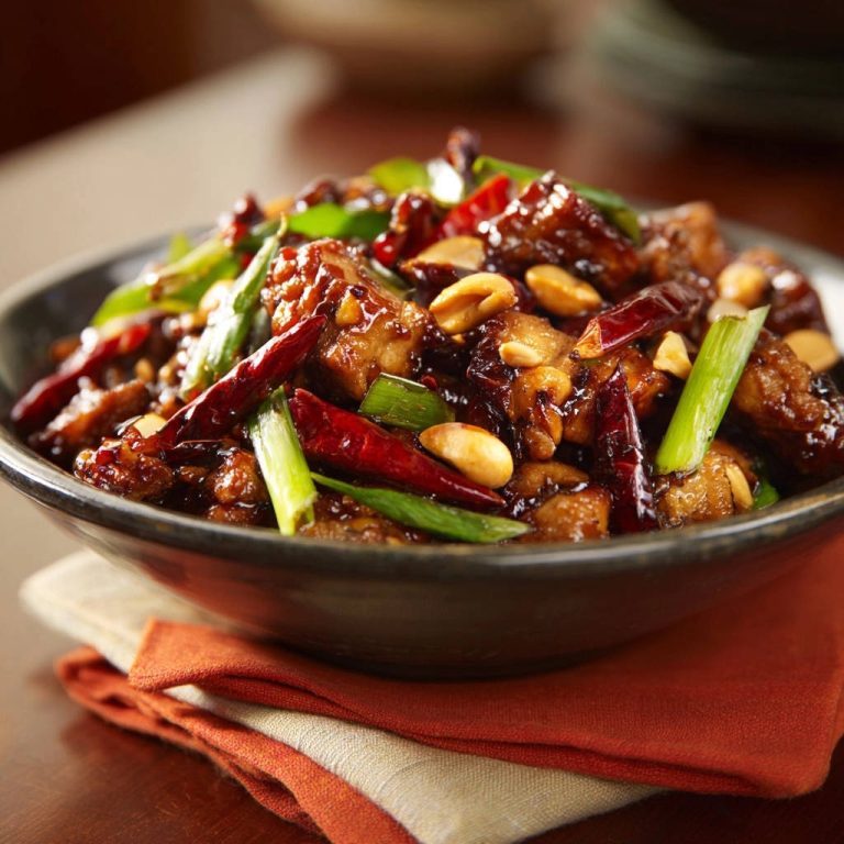 Scharfes Asia-Hähnchen mit Erdnüssen in Nahaufnahme: Knuspriges Hähnchen, geröstete Erdnüsse und Chilischoten in einer dunklen Soße.