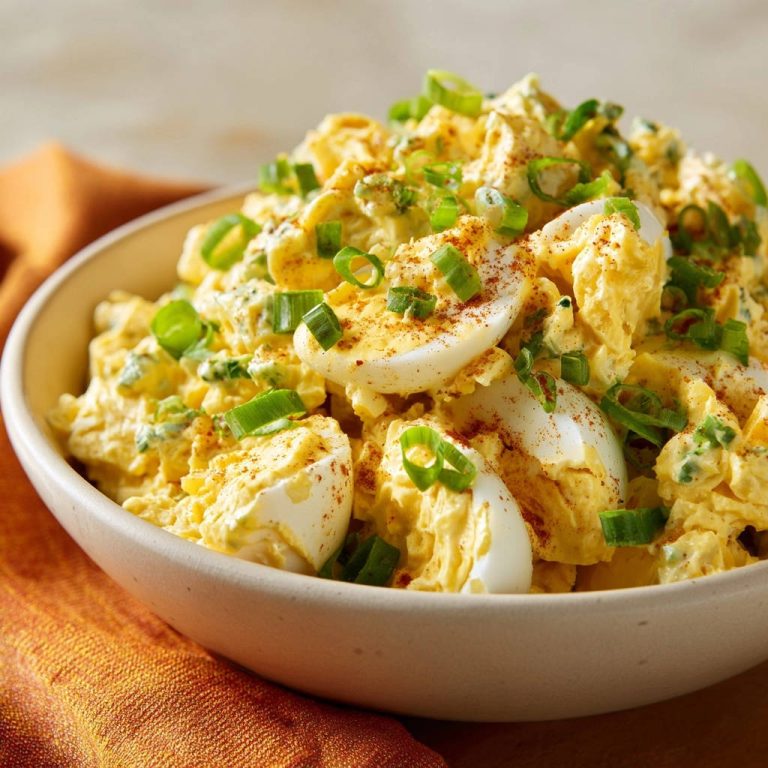 Cremiger Eiersalat mit Frühlingszwiebeln in einer Nahaufnahme, garniert mit frischen Frühlingszwiebeln und Paprikapulver.