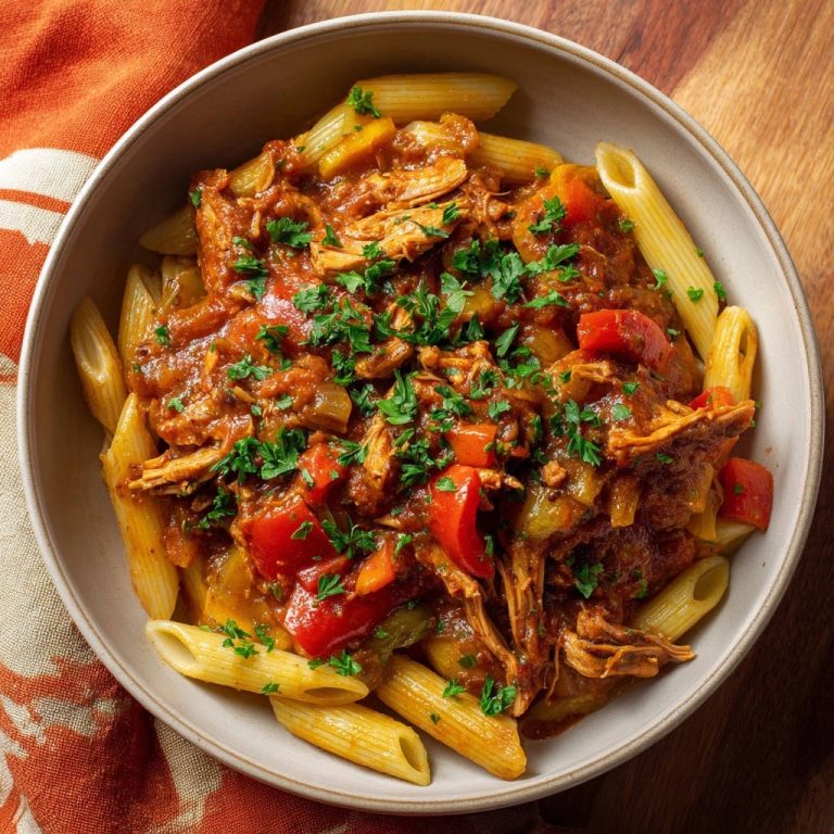 Herzhaftes Penne mit zartem Hähnchenragout in einer Schüssel, serviert mit frischer Petersilie und einem Blick von oben.