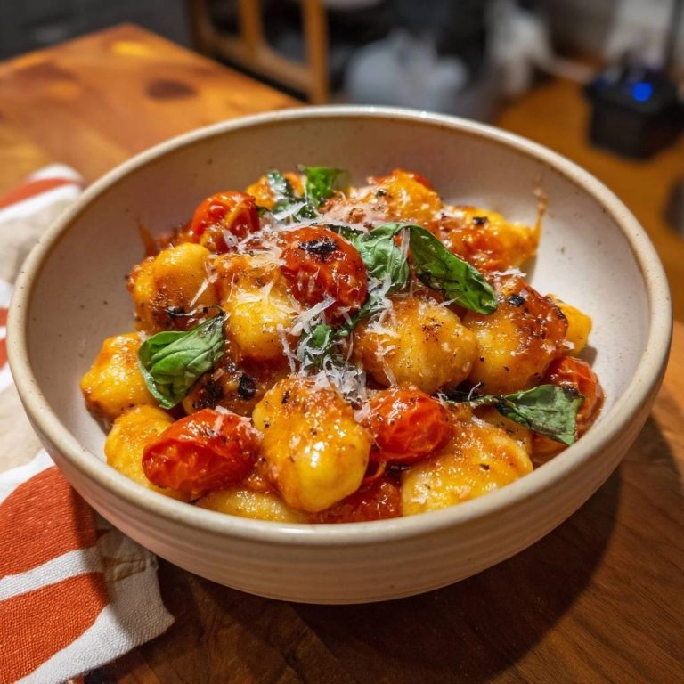 Knusprige Gnocchi mit gebratenen Tomaten, serviert in einer rustikalen Schüssel, garniert mit frischem Basilikum und Parmesan.