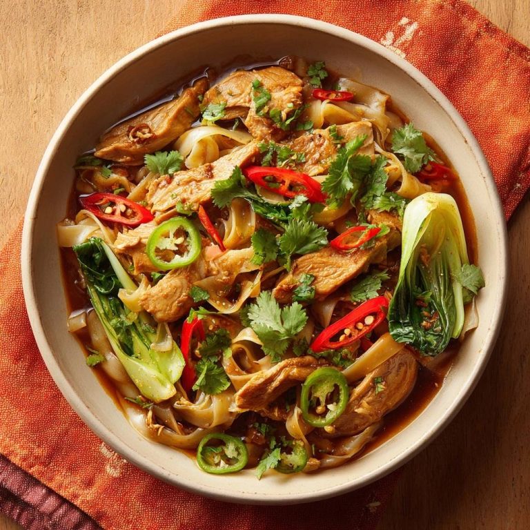 Saftige Hühner-Bok-Choy-Nudel-Suppe in einer Schüssel, serviert von oben mit frischen Kräutern und Chili-Scheiben.