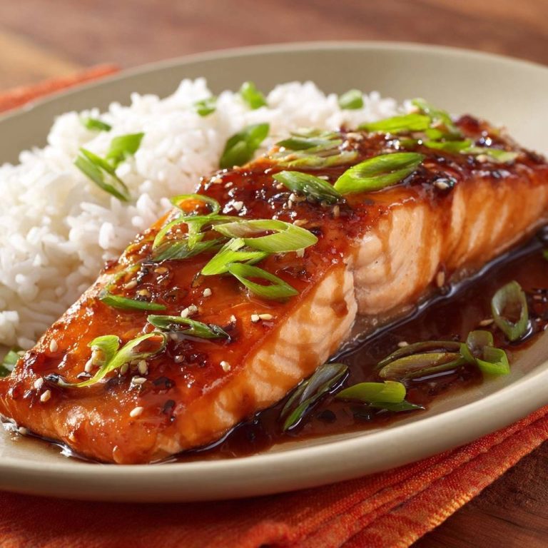 Teriyaki-Lachs mit Reis serviert auf einem Teller, garniert mit frischen Frühlingszwiebeln und Sesamkörnern, ein köstliches Gericht.