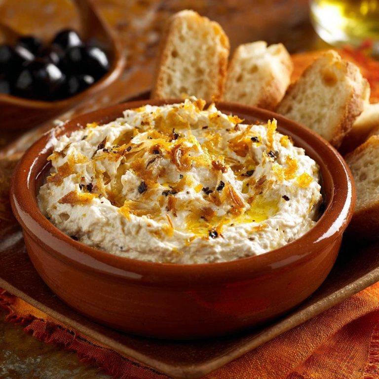 Cremiger Dip mit knusprigen Zwiebeln in einer rustikalen Schale, serviert mit Brot zum Dippen, nah aufgenommen für eine appetitliche Textur.