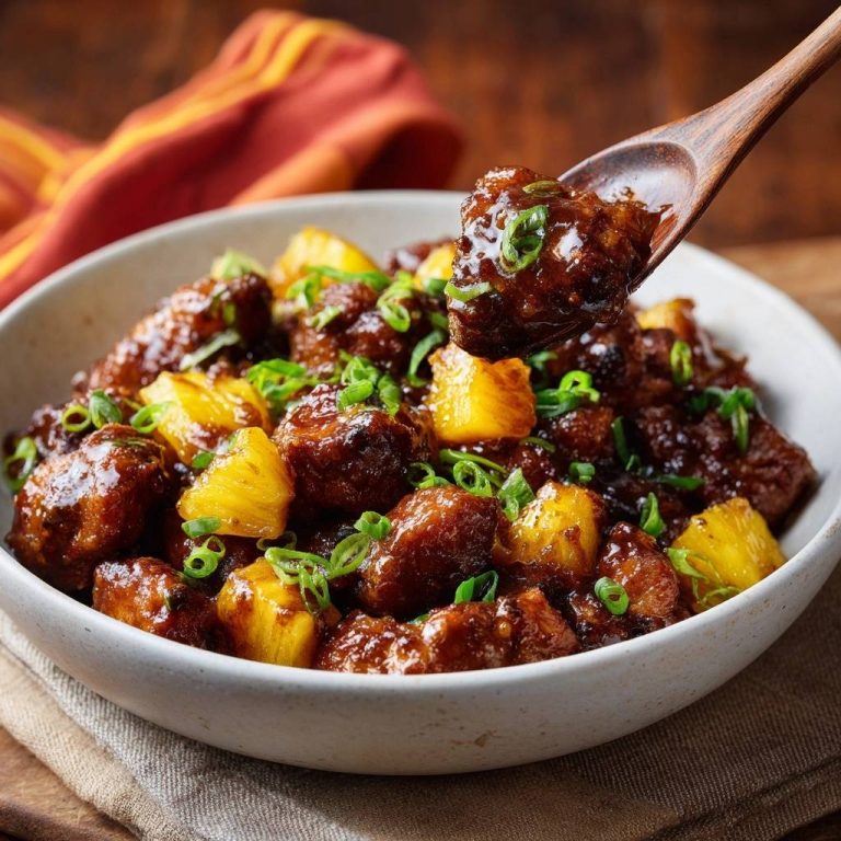 Glasiertes Ananas-Hähnchen in Nahaufnahme, serviert in einer Schüssel mit frischen Frühlingszwiebeln und Ananasstücken, wird von einem Holzlöffel präsentiert.