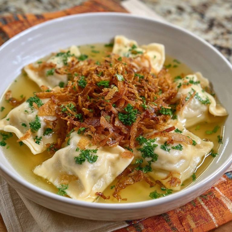 Ravioli in goldener Brühe mit knusprigen Zwiebeln, serviert in einer weißen Schüssel, garniert mit frischer Petersilie und knusprigen Zwiebeln.