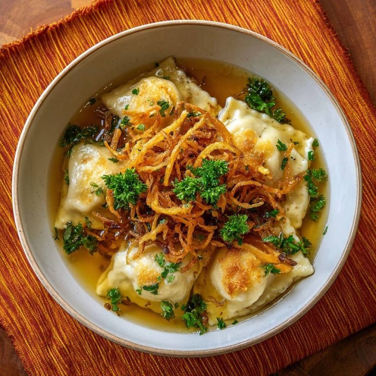 Schwäbische Maultaschen in goldener Brühe, von oben betrachtet, garniert mit knusprigen Zwiebeln und frischer Petersilie in einer hellen Brühe.