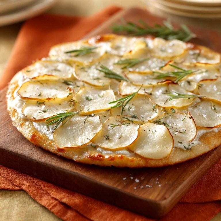 Cremig-knusprige Kartoffel-Rosmarin-Pizza in voller Pracht von oben betrachtet, mit frischen Rosmarinzweigen belegt. Die knusprige Pizza liegt auf einem Holzbrett.