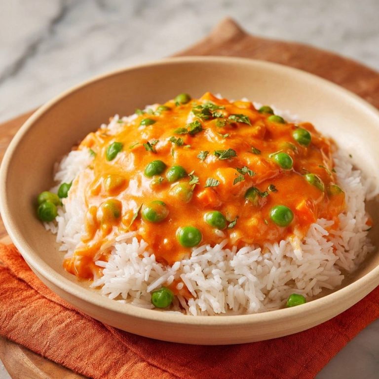 Cremiges Erbsen-Karotten-Curry mit Reis, serviert in einer cremefarbenen Schüssel, mit frischen Erbsen und Kräutern garniert.