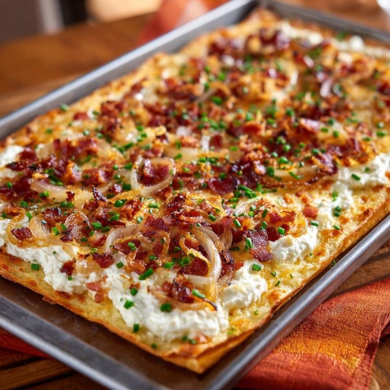 Knuspriger Kartoffelfladen mit Speck & Kräutercreme, serviert in einer Backform, mit knusprigem Speck und Zwiebeln belegt.