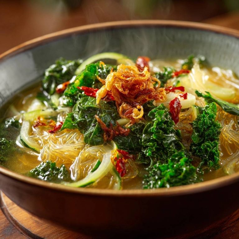 Asiatische Grünkohl-Glasnudelsuppe in Nahaufnahme mit dampfenden Aromen, die frisch zubereitet und mit knusprigen Zwiebeln garniert wurde.