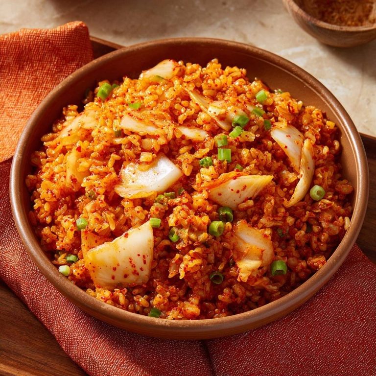 Koreanischer Kimchi-Fried-Rice, serviert in einer rustikalen Schüssel, mit frischen Frühlingszwiebeln garniert und von oben fotografiert.