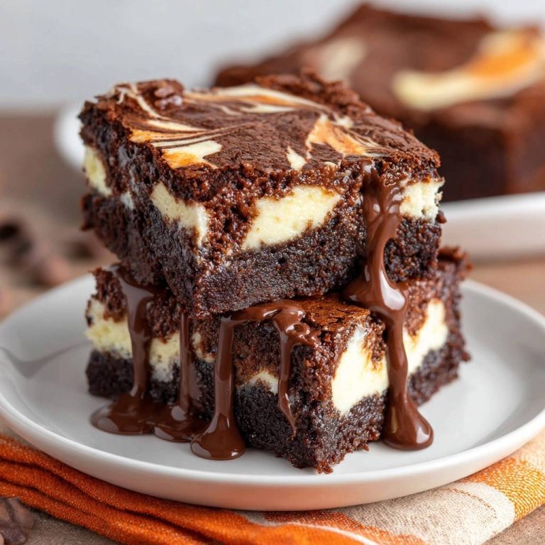 Marmorierte Cheesecake Brownies in Nahaufnahme, mit einem saftigen Querschnitt, der die cremige Käsekuchenschicht und den Schokoladenkuchen zeigt.