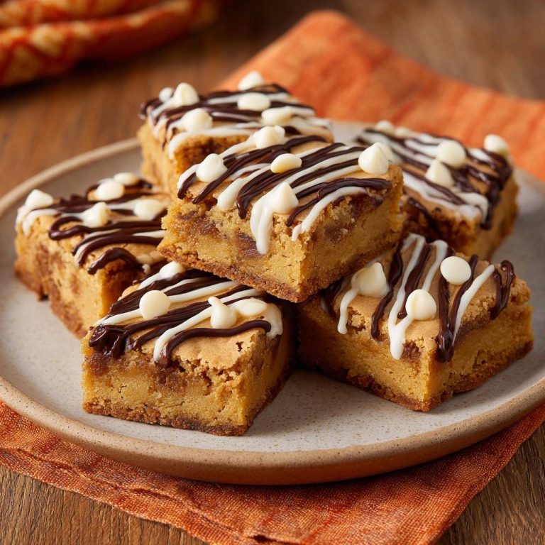 White-Chip Blondies mit Schoko-Drizzle serviert auf einem hellen Teller, garniert mit weißer Schokolade und Schokoladenstreifen.