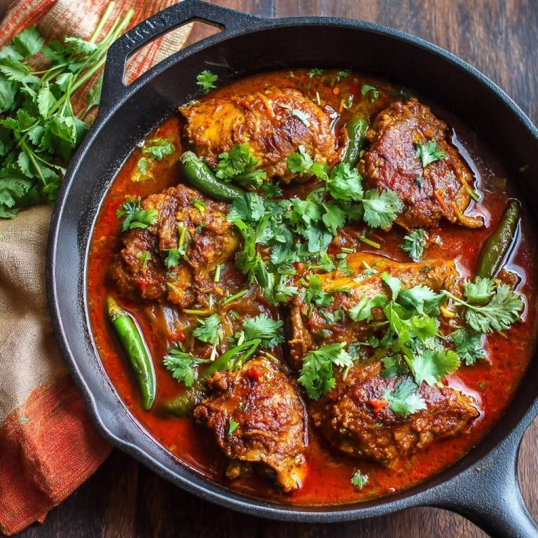 Würziges Pfannenhähnchen in Tomaten-Chili-Soße, serviert in einer gusseisernen Pfanne, garniert mit frischem Koriander und grünen Chilischoten.