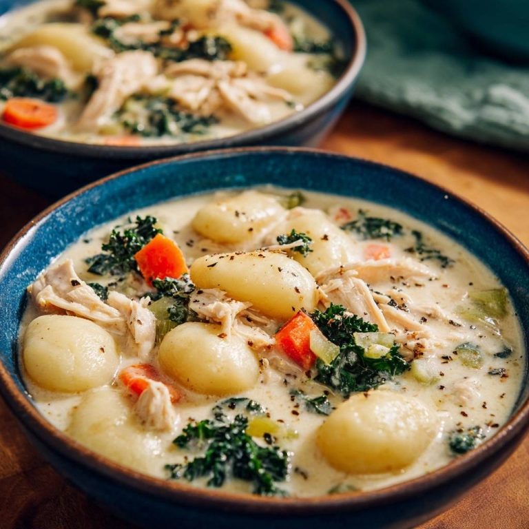 Cremige Gnocchi-Hähnchen-Suppe in einer Nahaufnahme, serviert in zwei blauen Schalen, mit frischer Petersilie und Gewürzen bestreut.