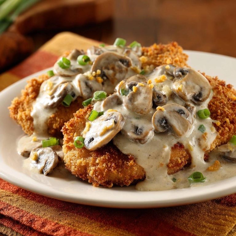 Knuspriges Hähnchen-Schnitzel mit Pilzrahm serviert auf einem weißen Teller, garniert mit frischen Pilzen und Schnittlauch. Ein köstliches Gericht.