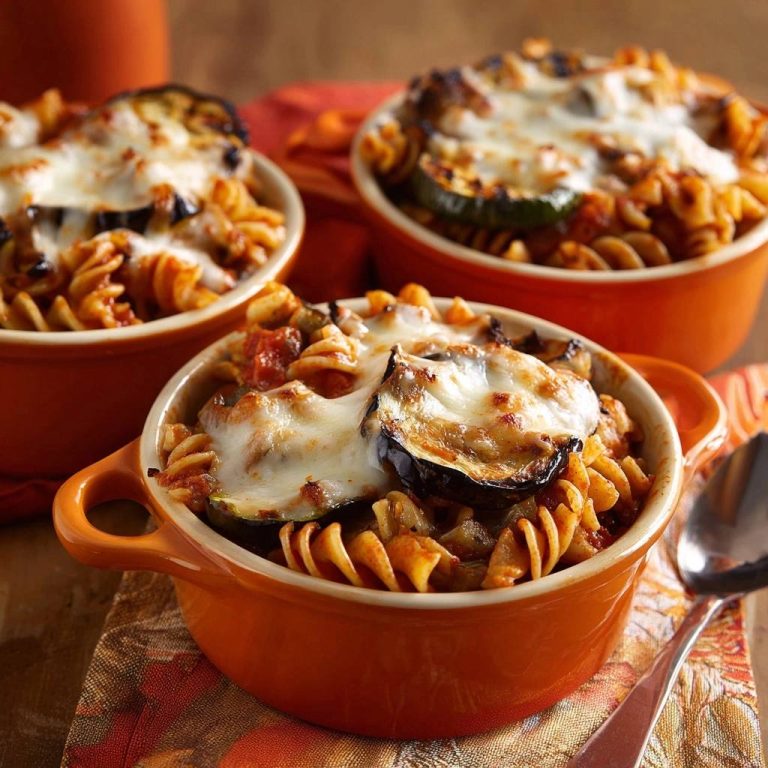 Mediterraner Pasta-Auflauf mit Aubergine serviert in einzelnen Schalen, bedeckt mit geschmolzenem Käse und gegrillter Aubergine.